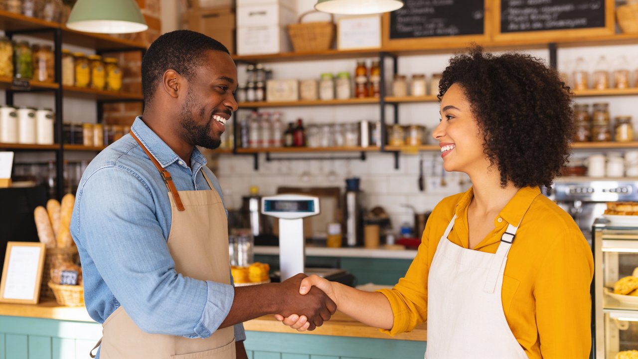 Small business owner reviewing business bank deposit statements on a laptop at a shop counter