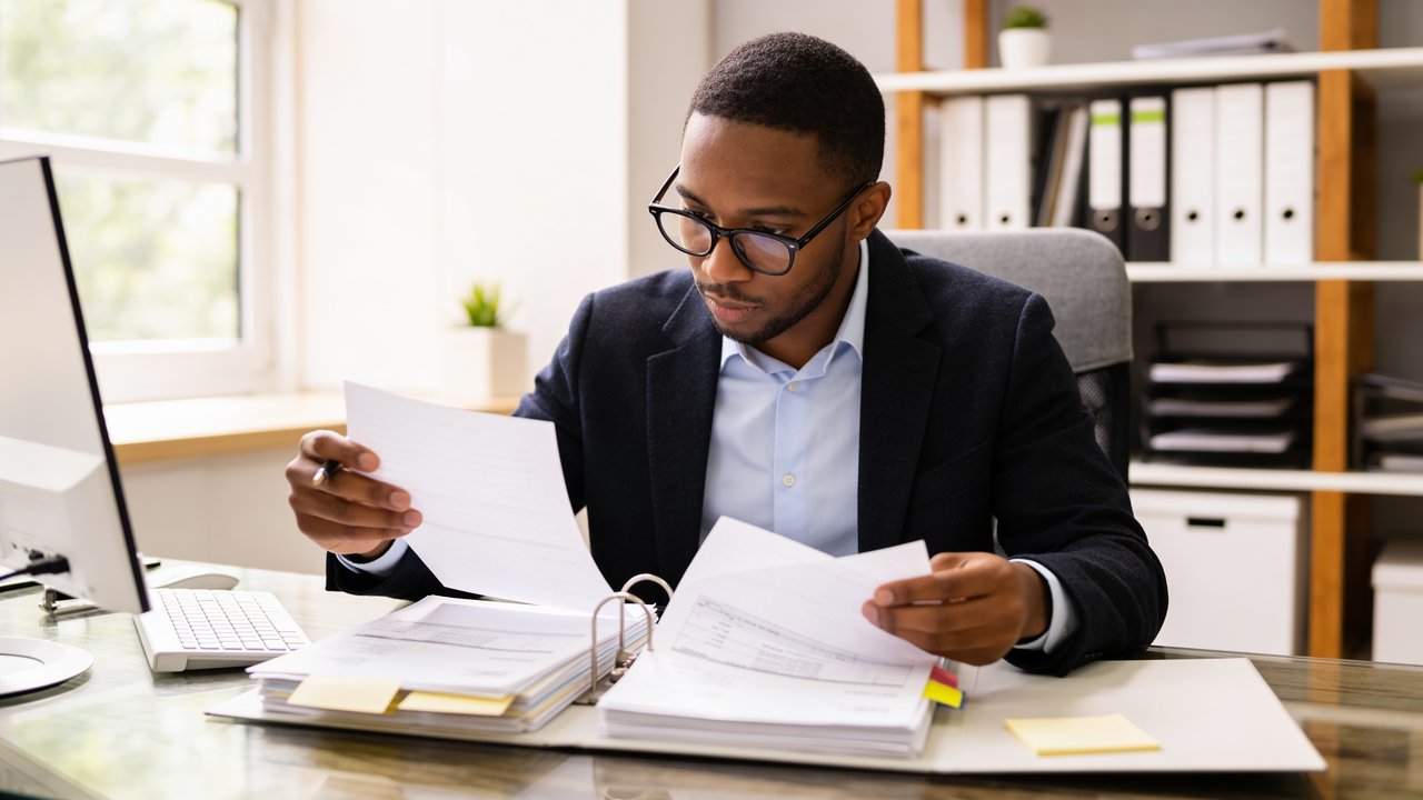 Business owner reviewing accounts receivable and invoices to compare recourse and non-recourse factoring